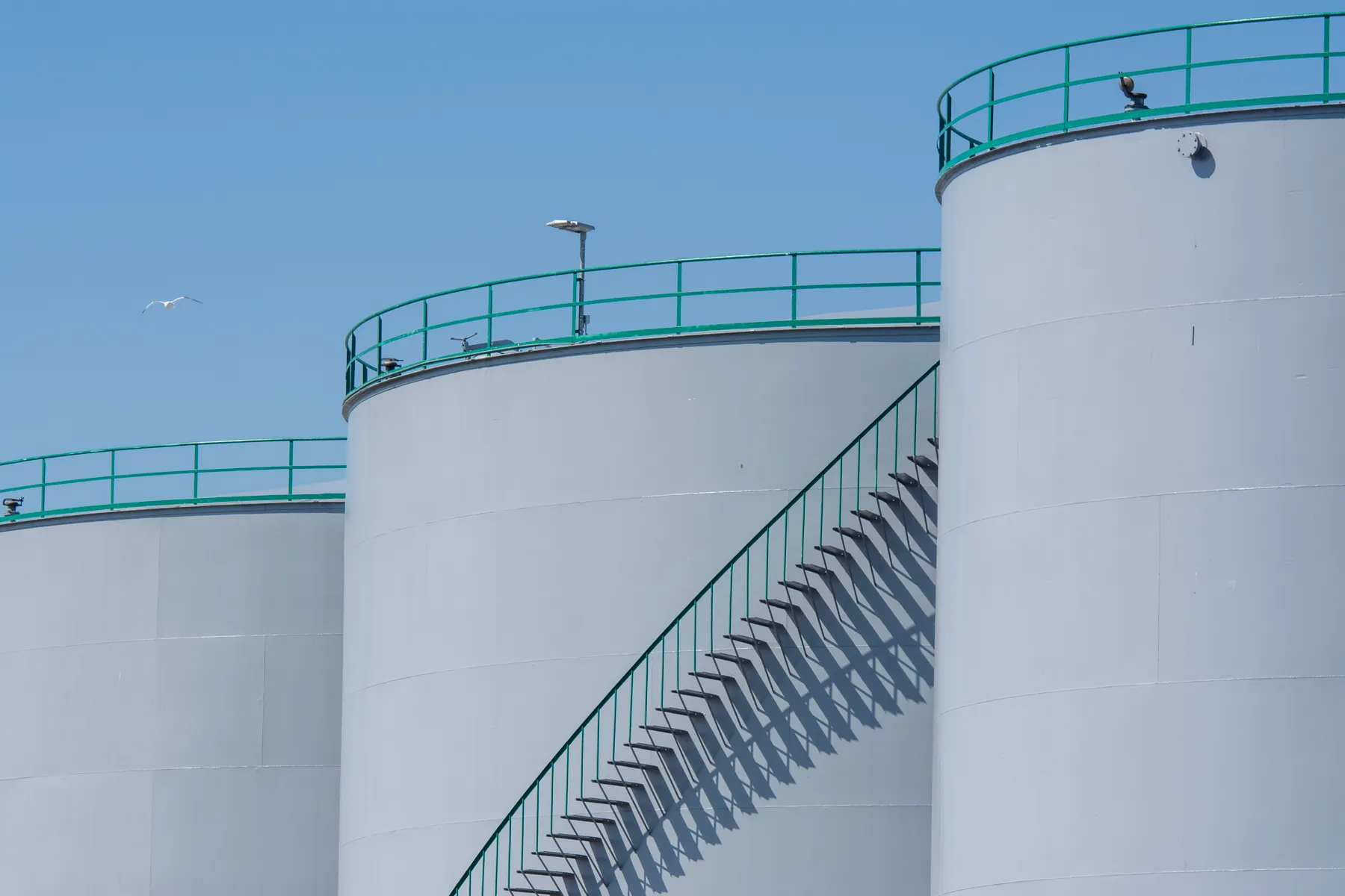 Storage tanks with external stairways under a blue sky